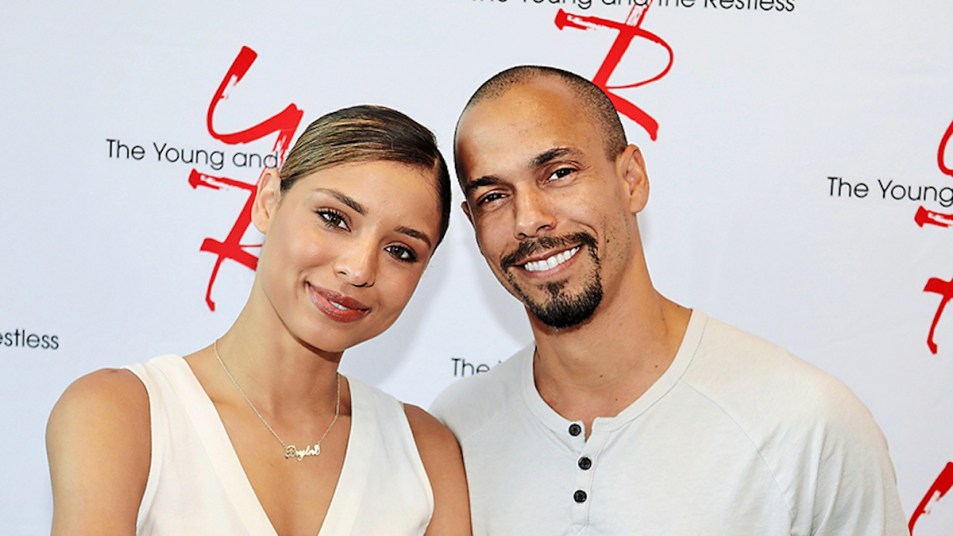Y&R star Brytni Sarpy and Bryton James posing in front of The Young and the Restless logos